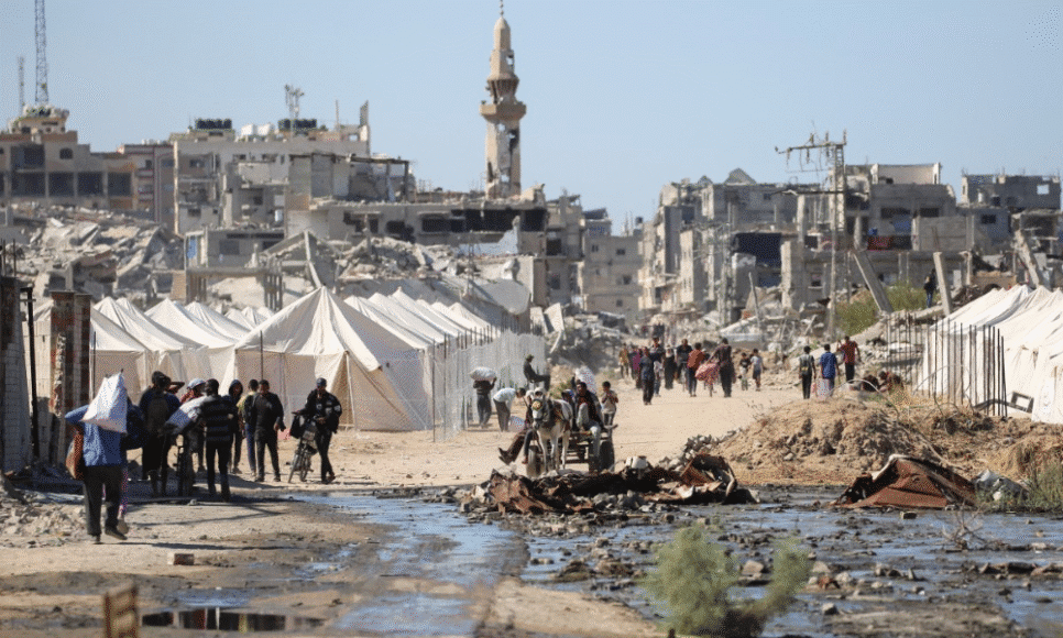 Palestinos deslocados passam por tendas e prédios destruídos enquanto retornam para suas casas, no centro da Faixa de Gaza