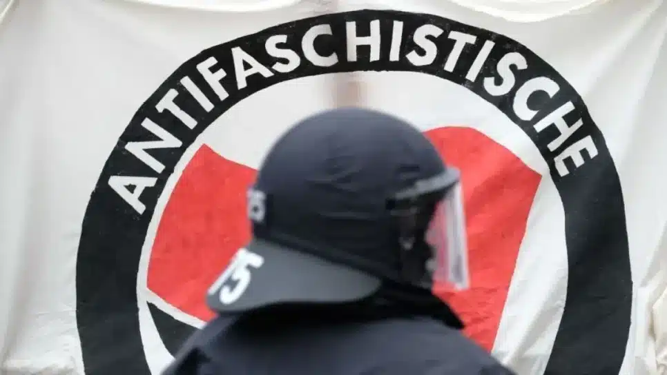 Policial em frente a uma faixa da Antifa durante uma manifestação de esquerda na Alemanha