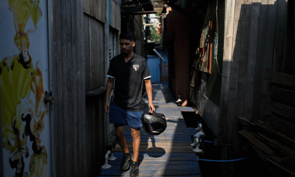 Um homem vestindo a camisa do time de futebol São Paulo caminha pela Vila da Barça, um bairro de palafitas em Belém, no Pará, Brasil, em 5 de novembro de 2025. (Foto de Mauro PIMENTEL / AFP)