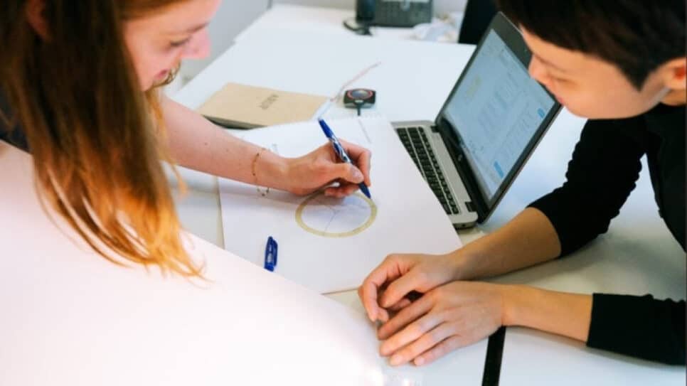 pessoas em uma mesa com papeis e computador