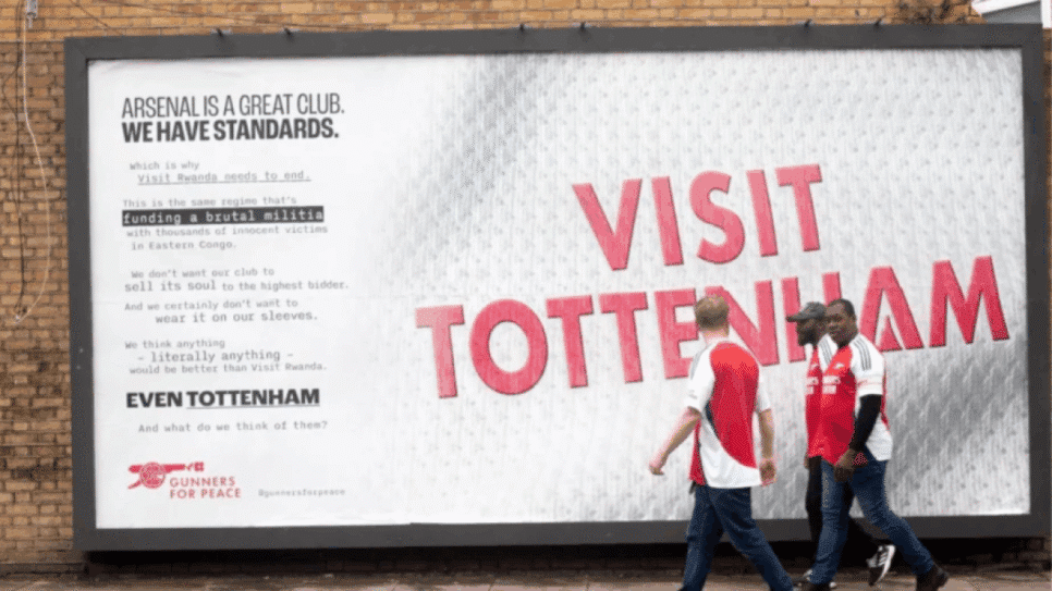 Gunners for Peace instalam outdoor satírico “Visit Tottenham” perto do Emirates Stadium em protesto contra o patrocínio; mensagem critica o governo de Ruanda e cita o rival no dérbi do norte de Londres.