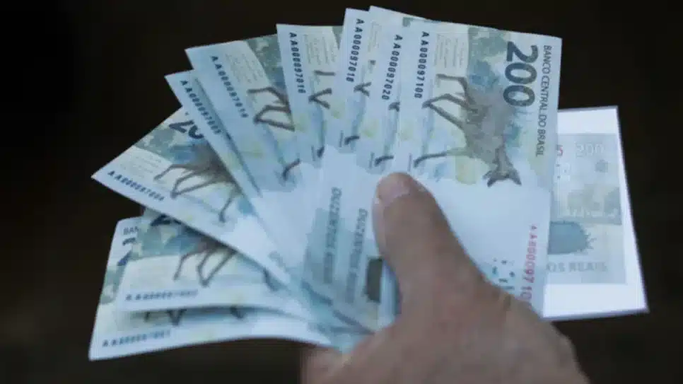 homem segura notas de R$ 200 dinheiro