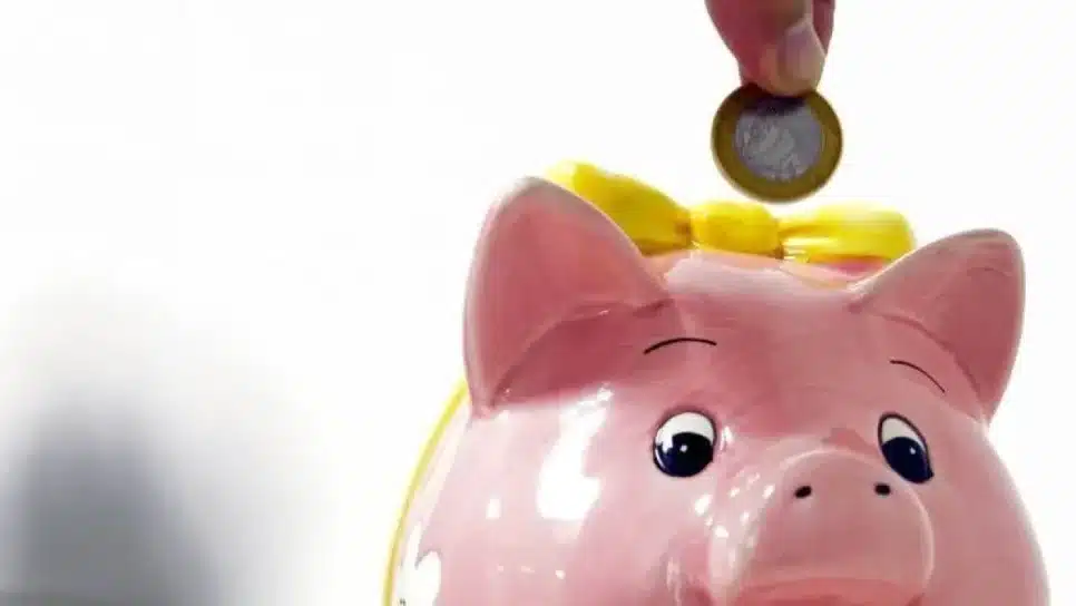 Pessoa colocando moeda em cofre porquinho