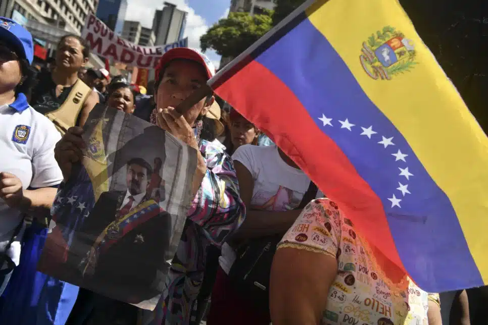 Um manifestante pró-governo segura uma faixa com a imagem de Nicolas Maduro e a bandeira venezuelana durante um comício em Caracas um dia após a captura de Nicolas Maduro pelas forças dos EUA