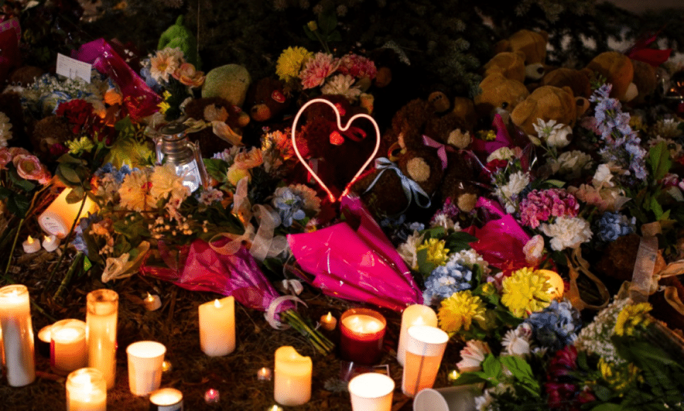 Flores e velas formam um memorial enquanto pessoas da comunidade prestam homenagem durante vigília às vítimas do massacre em uma escola no Canadá