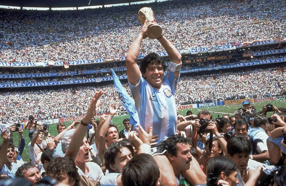 Com o troféu em mãos, Maradona é carregado pelos companheiros após conquistar a Copa com a Argentina