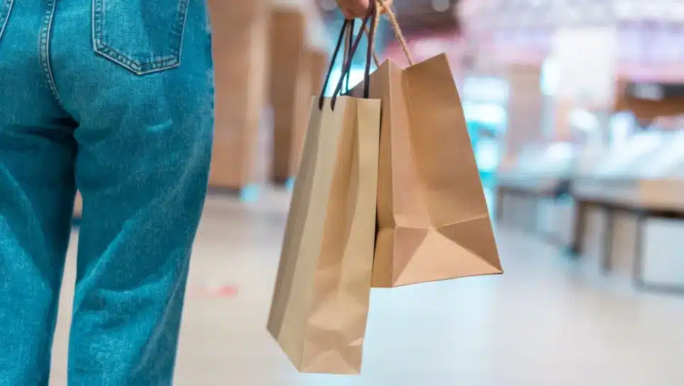 Pessoa segura sacolas de compras em um shopping