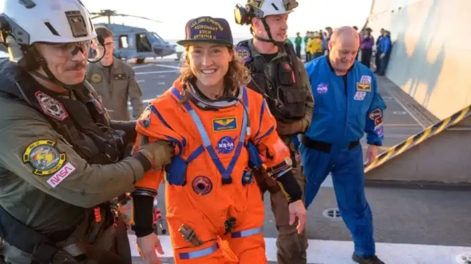 A astronauta da Nasa Christina Koch, especialista da missão Artemis 2, é auxiliada a sair do helicóptero que a levou ao navio militar USS John P. Murtha, onde passou por avaliação médica na 6ª feira (10.abr.2026)