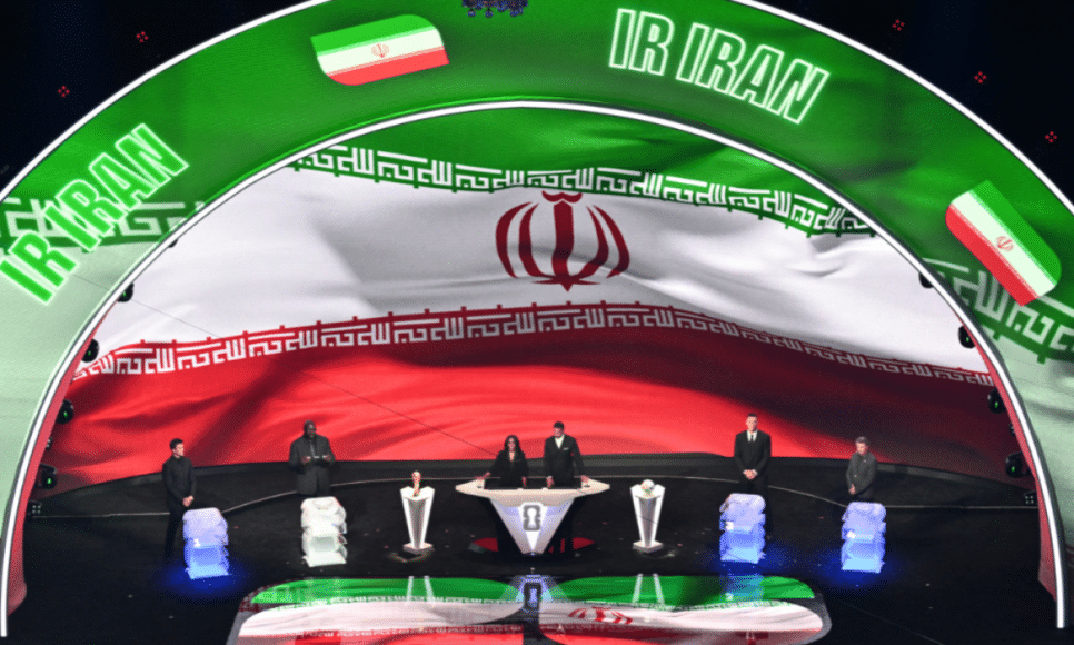 A bandeira do Irã é exibida em um telão durante o sorteio da Copa do Mundo FIFA de 2026, que será realizada nos Estados Unidos, Canadá e México, no Kennedy Center, em Washington, D.C., em 5 de dezembro de 2025. (Foto de Roberto Schmidt / AFP)